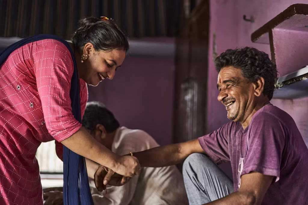 A health worker checking on a smiling man at his home
