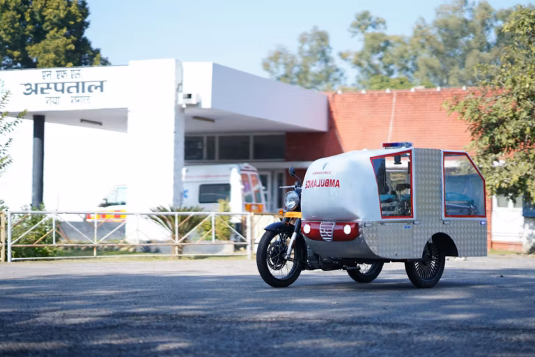 A district hospital building with a Hindi sign and a bike ambulance outside