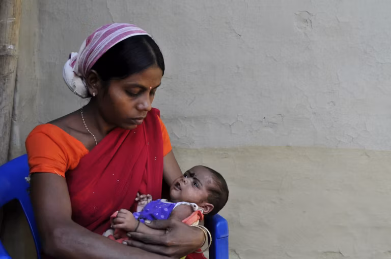 A mother in a red sari holding her baby