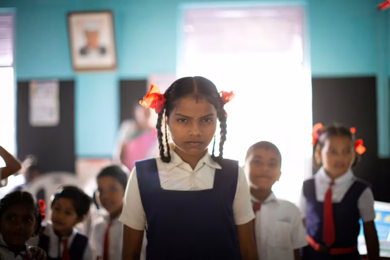A schoolgirl in uniform standing in her classroom