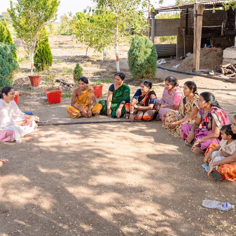 Women sitting on the ground in a circle in a courtyard