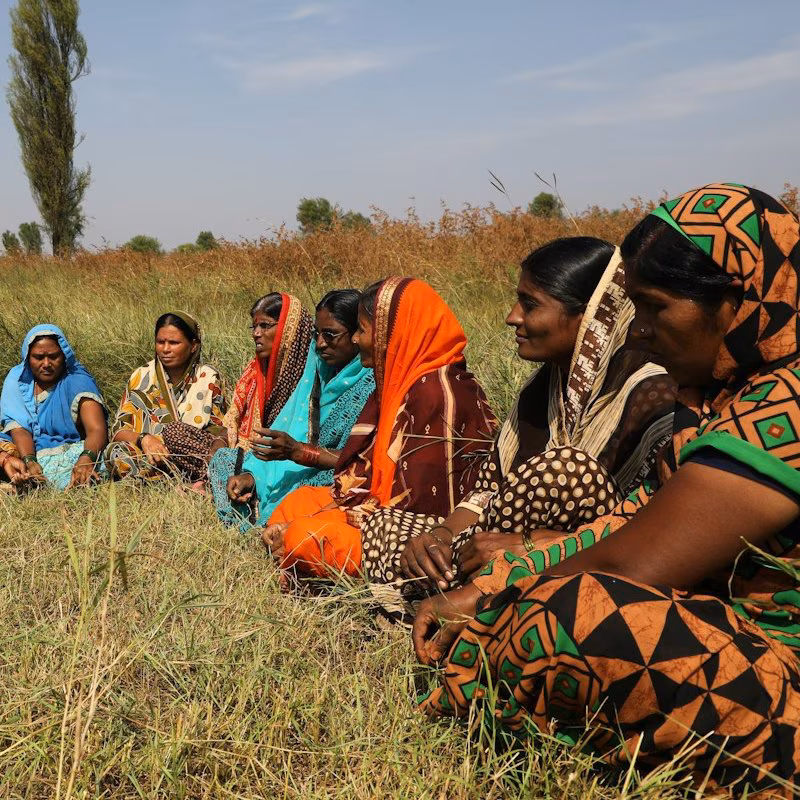 Women sitting in a circle on a field, listening